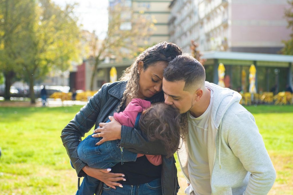 A family enjoying a warm embrace outdoors in a sunny park setting, spreading love.